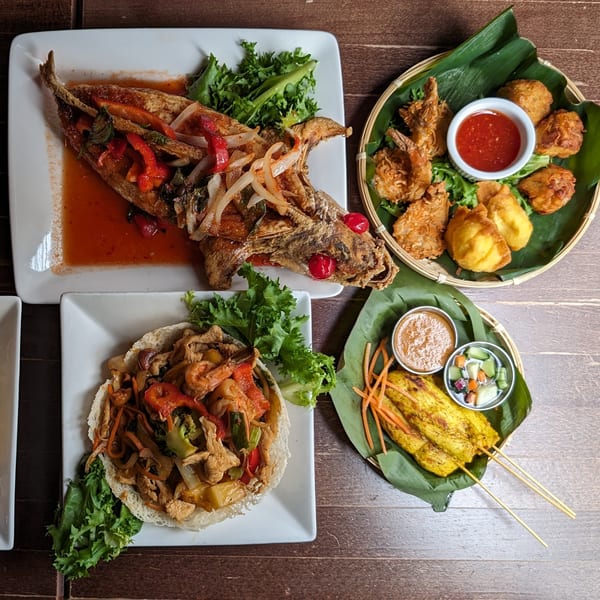 A top-down view of various Thai dishes, including fried fish, satay, and stir-fry.
