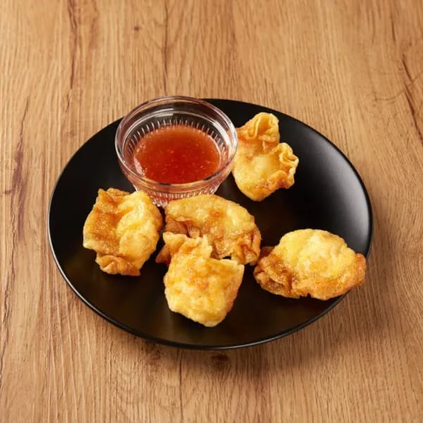 Crispy fried wontons and a small bowl of sweet chili dipping sauce on a black plate.